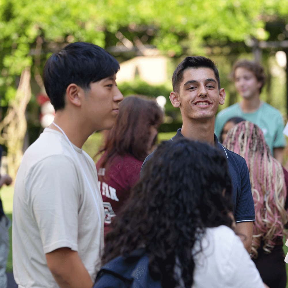 A male student looks at the camera during a group exercise at summer orientation on the Lincoln Center campus