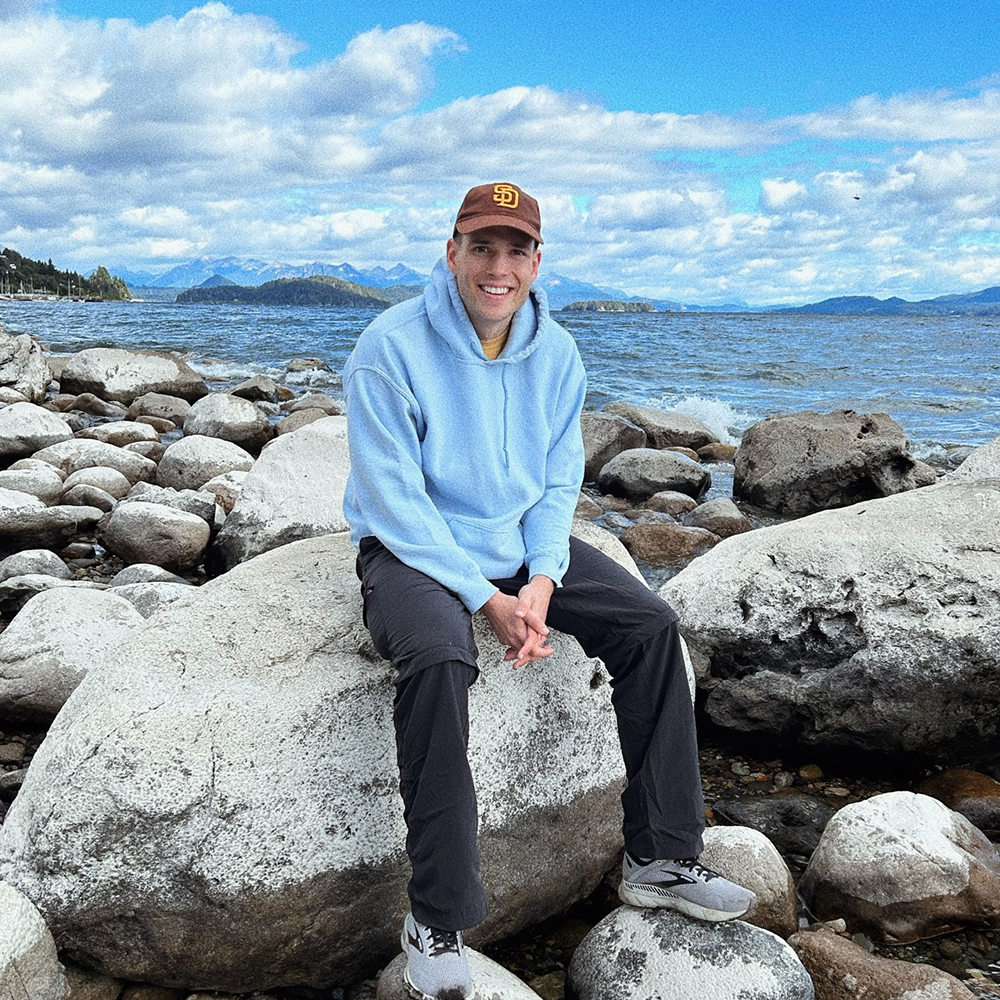 Student sits on rock in front of ocean