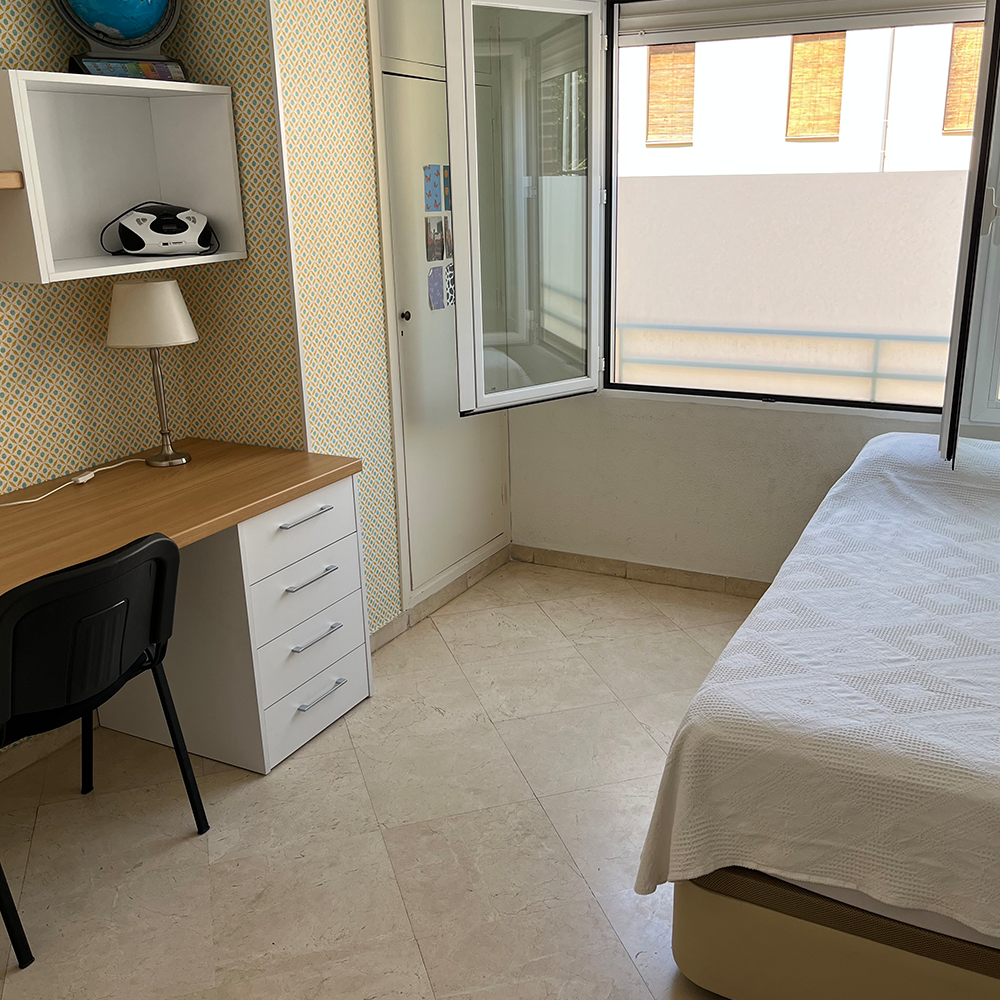 Image of a bed, desk, and window in student housing