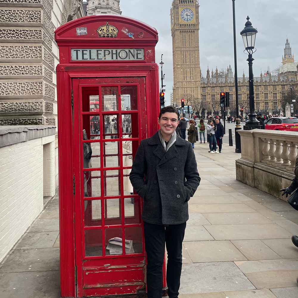 Student stands in front of UK telephone booth