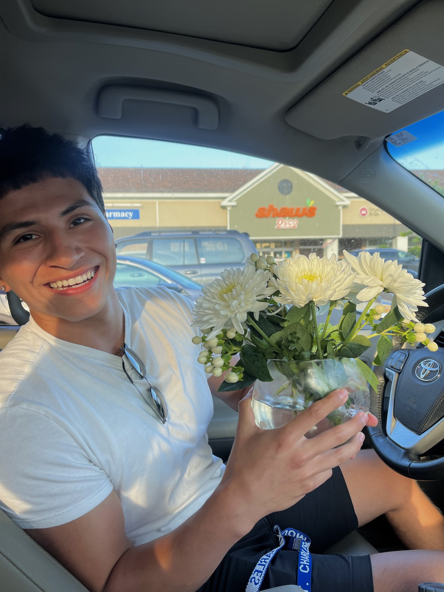 Matt sitting in a car holding white flowers