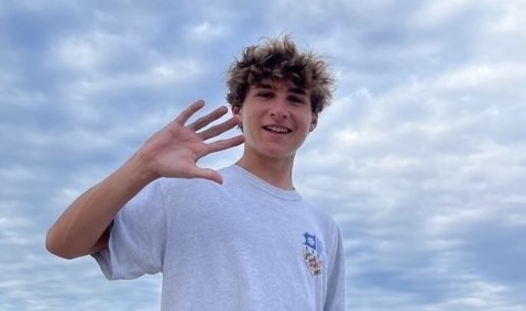 Student waving at the beach