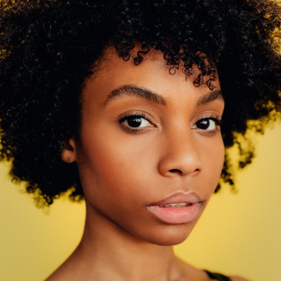 Michele Lee headshot with a vibrant yellow background