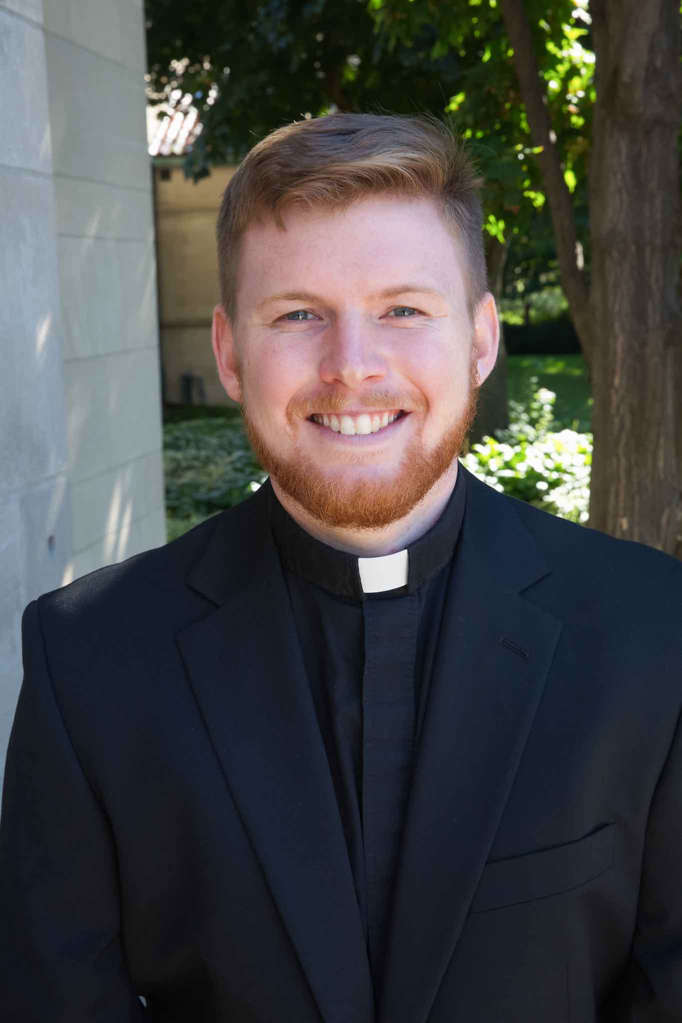 A headshot of Taylor Fulkerson, smiling at the camera with a clerical collar