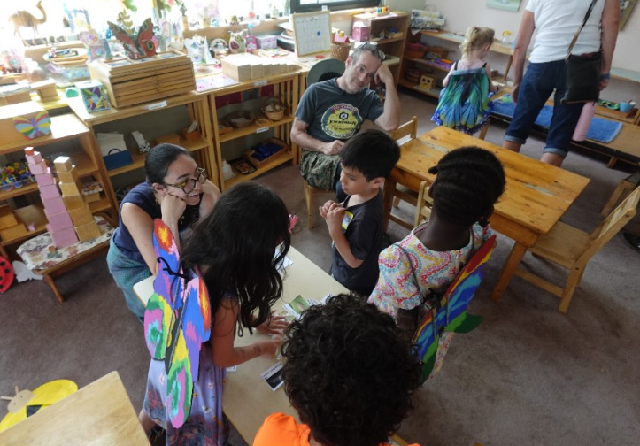 A member of the Initiative knelt down and interacting with several kids around a table