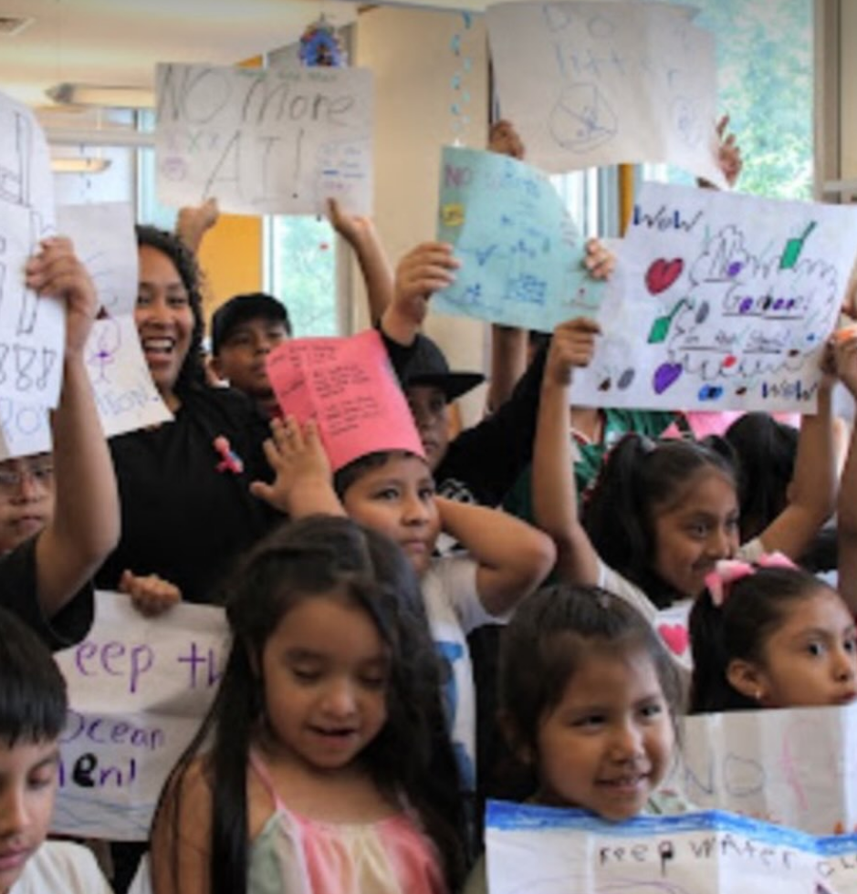 A group of elementary school children holding up signs