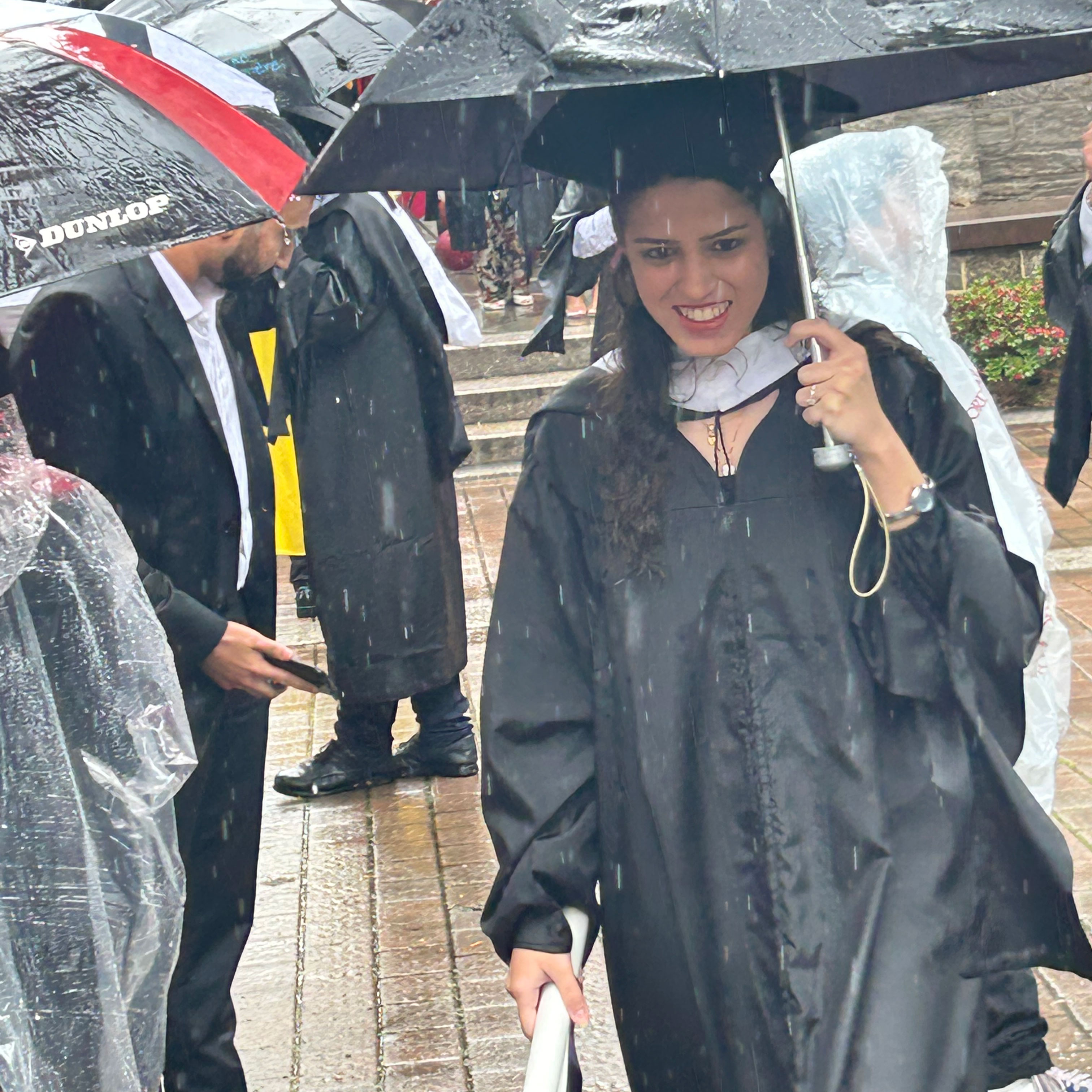 Nisa Khurram Hafeez at Commencement with umbrella in the rain