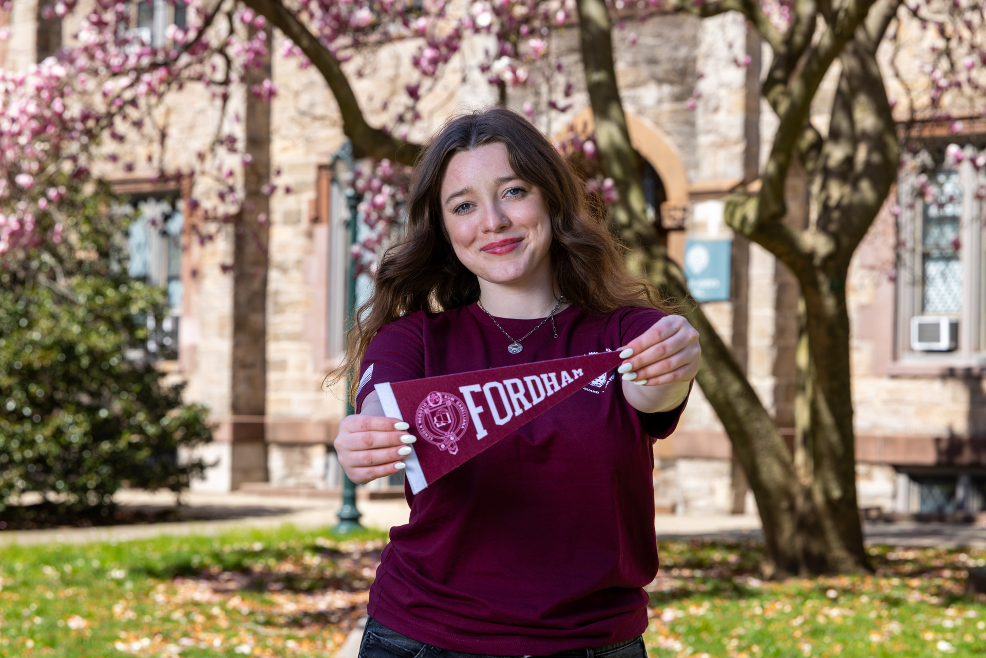 Female military-connected student holds a Fordham pennant.