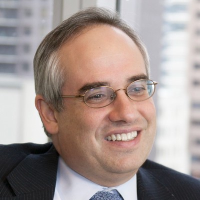 Antonio wearing business attire and smiling wearing glasses