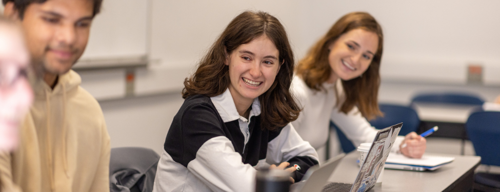 students sit at a desk smiling