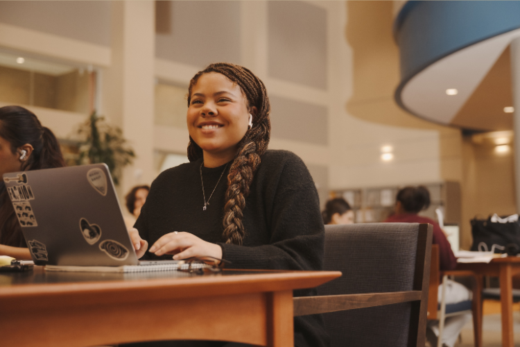 a student working on their laptop and smiling