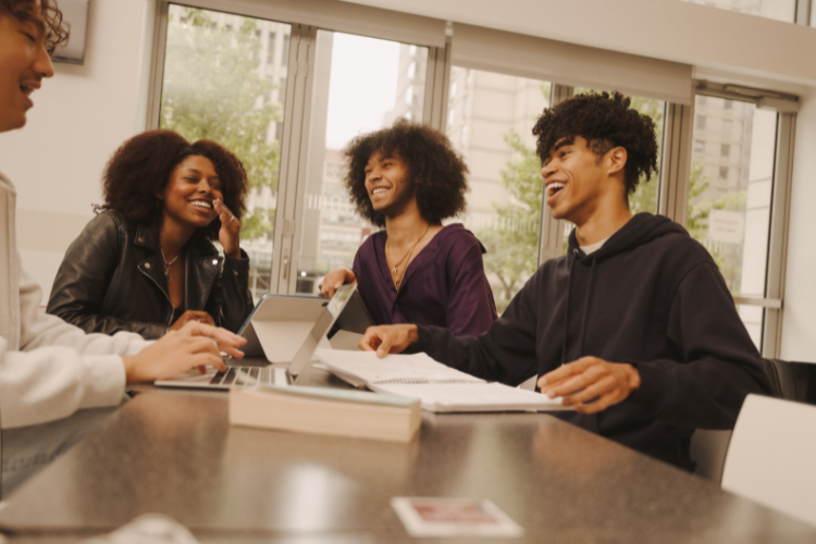 students sitting around a table, talking and laughing