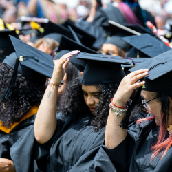 graduates fixing their caps sitting at Edwards Parade.