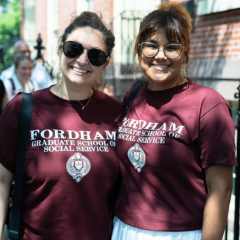 two students smiling and wearing maroon fordham gss shirts