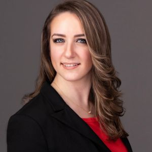 A woman with long hair wearing a red shirt and black blazer