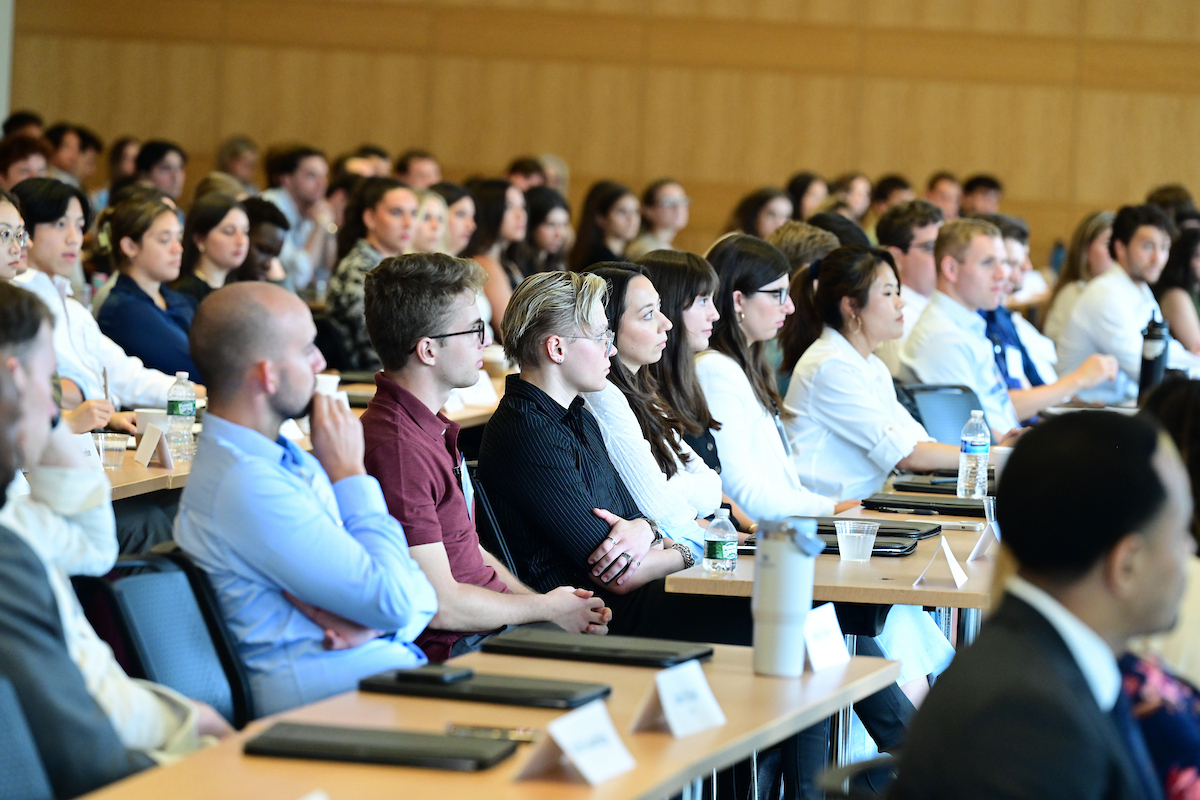 Group of students seated at a long table facing the same direction.