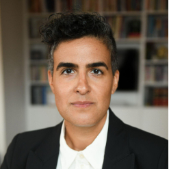 A person with short hair wearing a white shirt and black blazer.