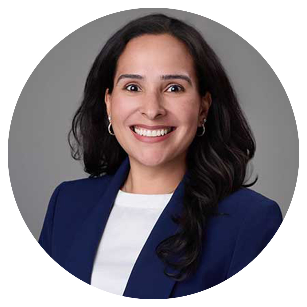 A woman with long, dark hair wearing a white shirt and blue blazer.
