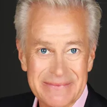 A man wearing a dark blazer and pink shirt.