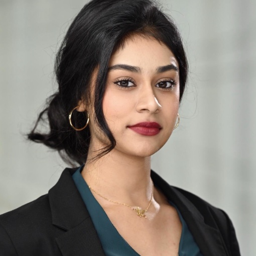 A woman wearing a black blazer and green shirt.