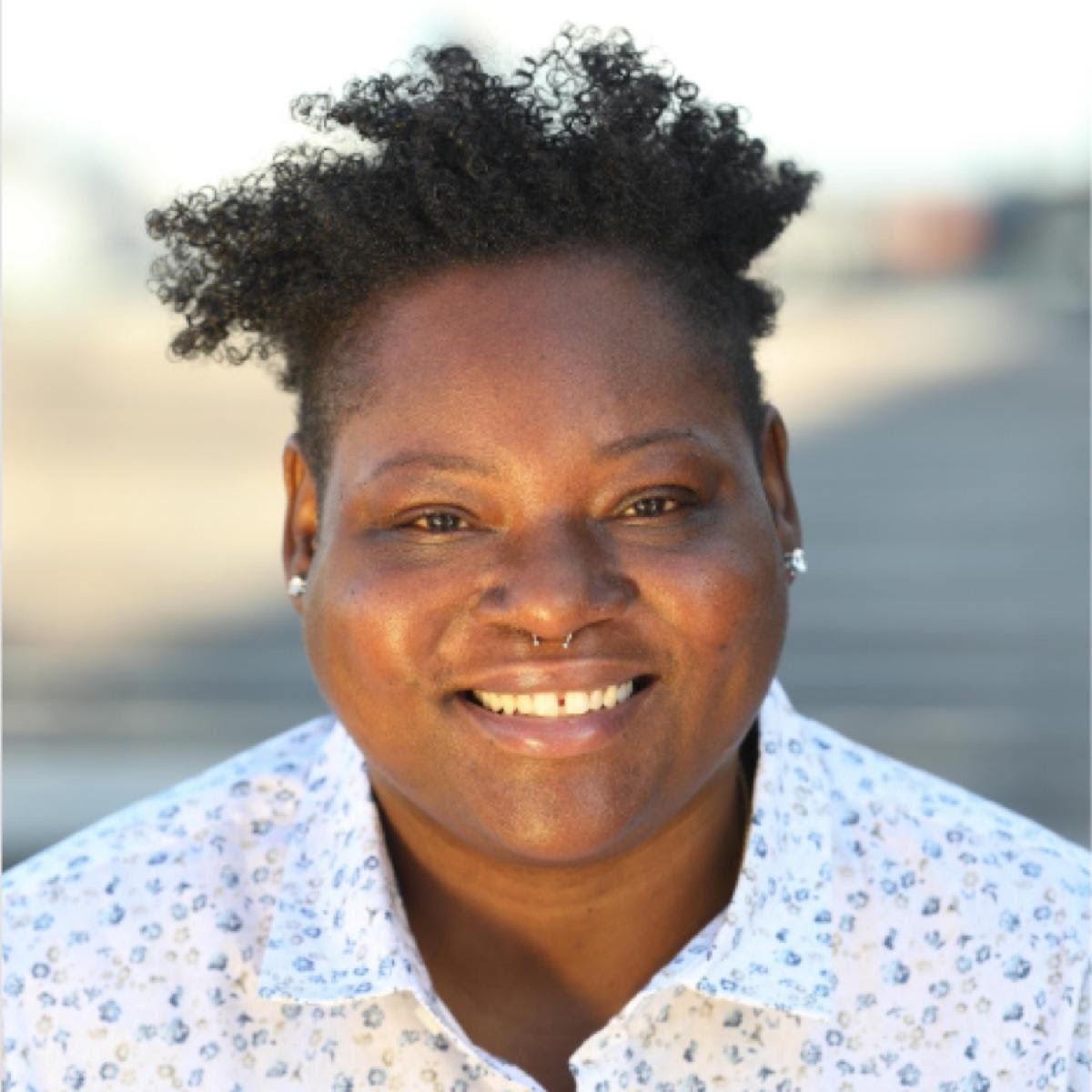 A woman with short hair wearing a patterned white shirt.
