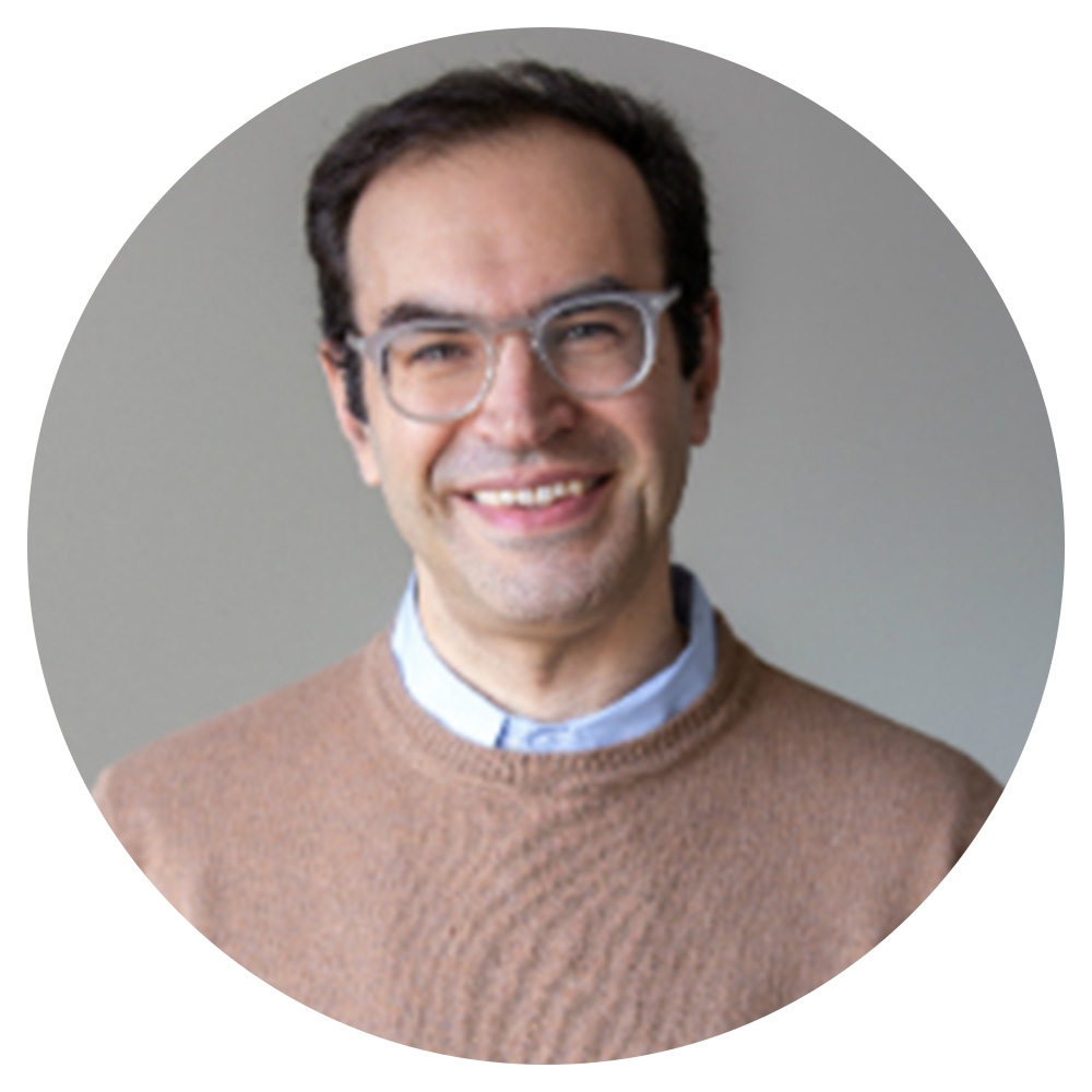 A man wearing glasses and a tan sweater.