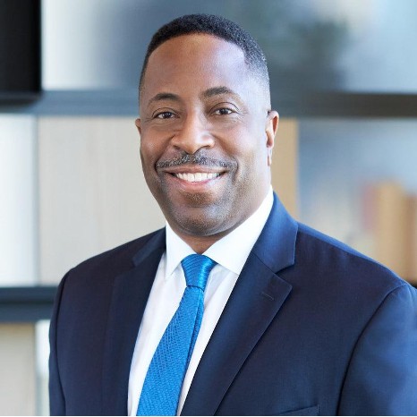 A man wearing a dark blue suit inside an office.