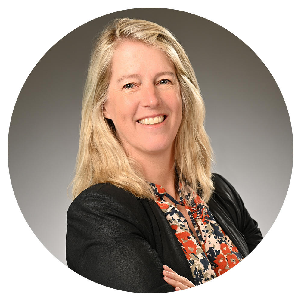 A woman with blond hair wearing a patterned shirt and black blazer.