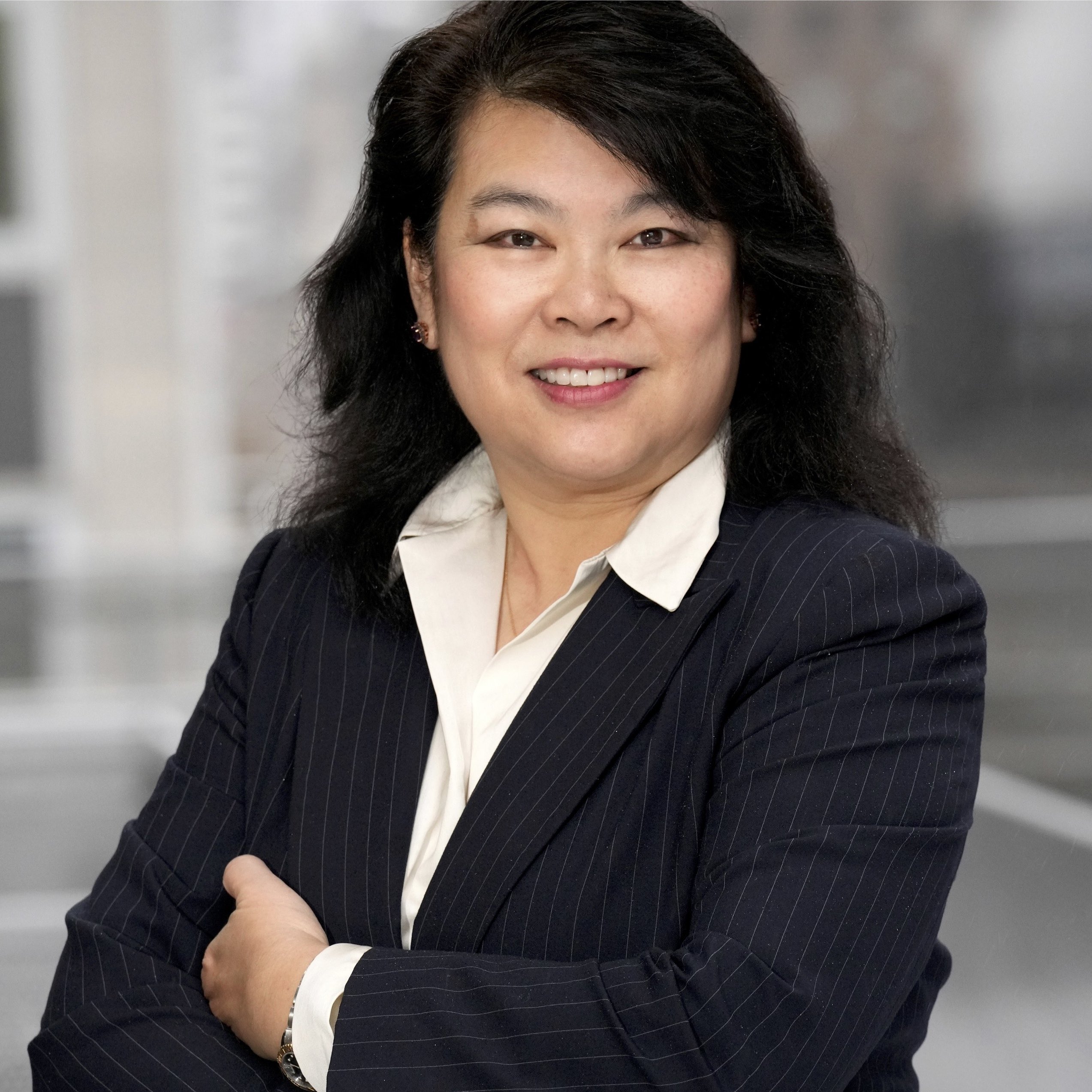 A woman with dark hair wearing a black blazer and white shirt.