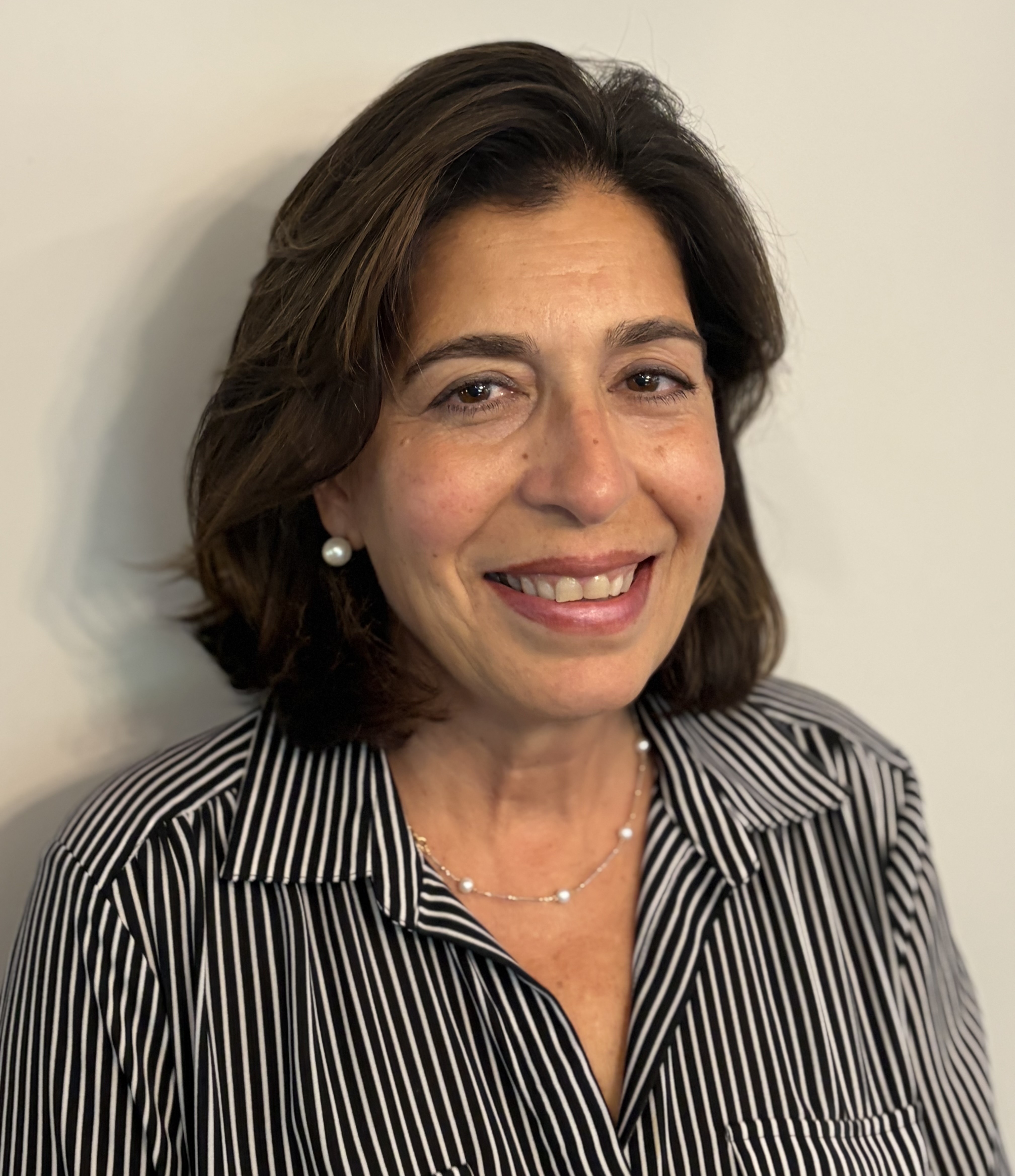 Tina Petrillo, a woman with dark brown hair smiling against a white background