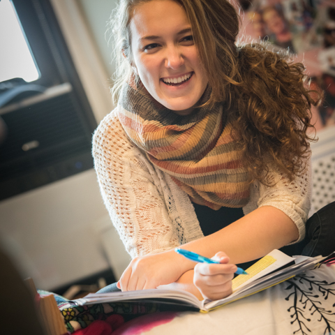 Female student taking notes in dorm room - LG