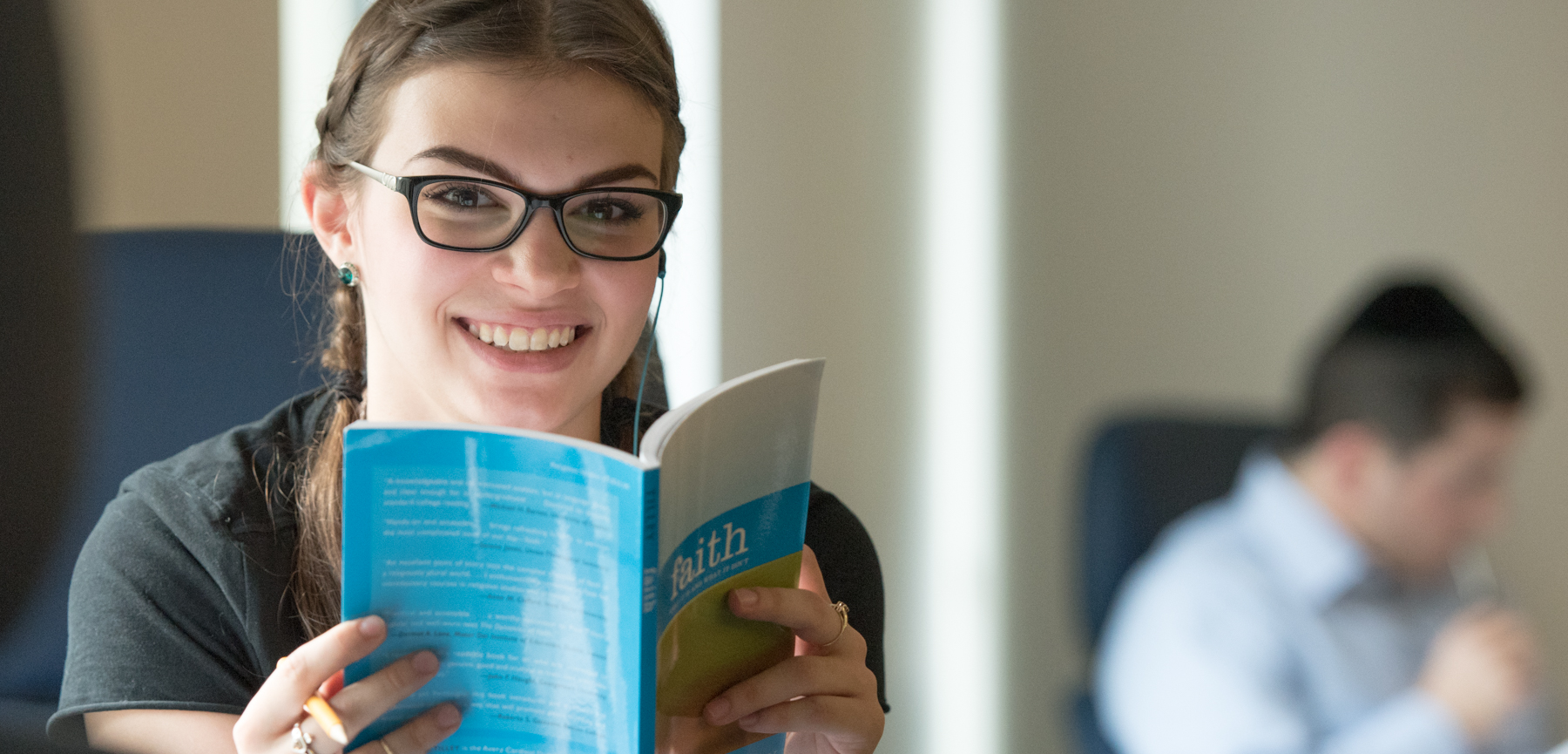 Female Student Peers over Text Book