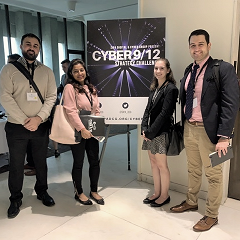 Four students around a sign for the 2018 NYC Cyber 9/12 Challenge