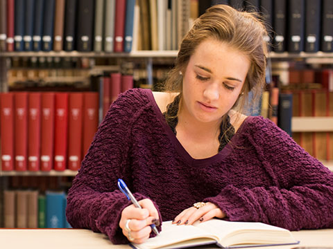 Female Student Writing in Library