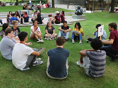 A group of students sitting in a circle outside during orientation