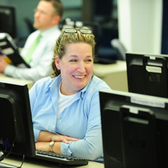 Adult female PCS student smiling at neighbor in computer lab