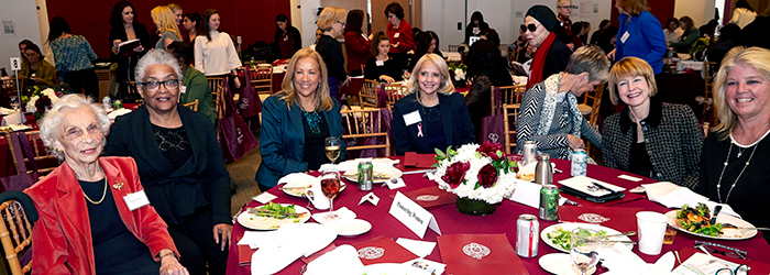 Women sitting and smiling at the camera at the women's philanthropy summit