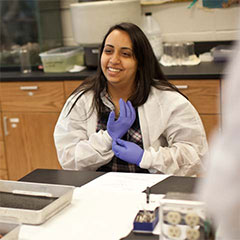 Female student putting on gloves in lab