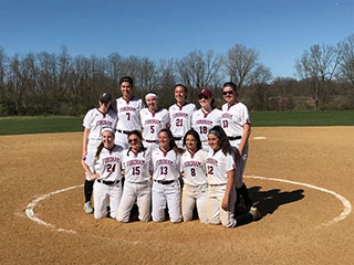 Softball team smiling for group photo on field.