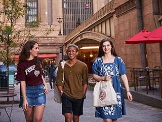 Three female students walking with bags outside of Grand Central Station